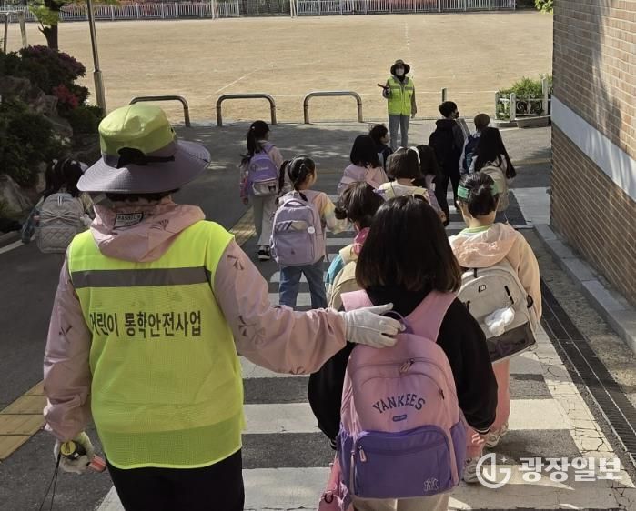 초등학교 학생들이 워킹스쿨버스 안전지도사와 함께 등교하고 있다.